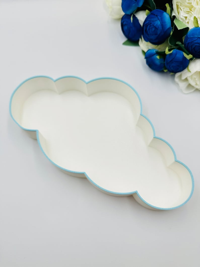 May include: A white cloud-shaped tray with a light blue border. The tray is empty and is sitting on a white surface.
