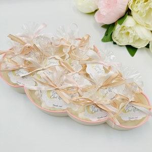 May include: A cloud-shaped tray filled with small white favors wrapped in clear cellophane bags tied with gold ribbon and a small tag that says "We're Having a Cloud Nine Baby Shower! Thank you!"