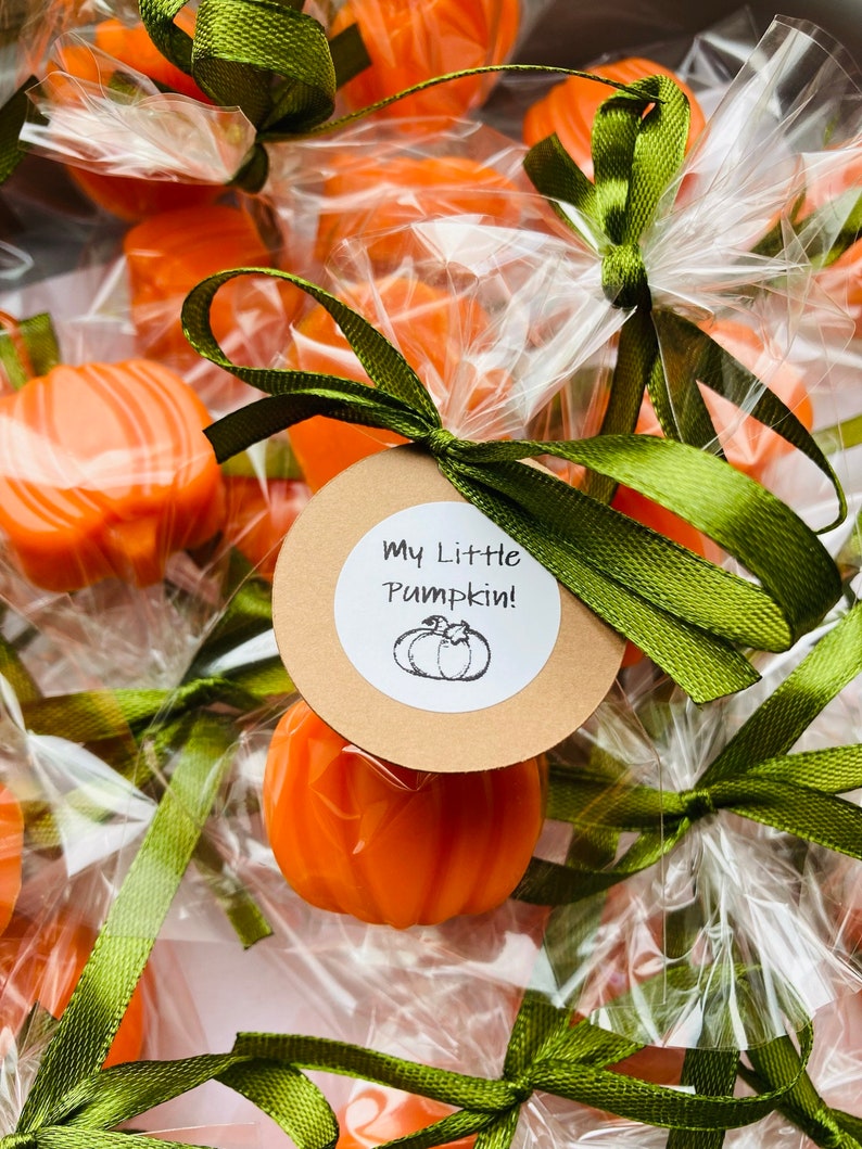May include: A group of small orange pumpkin-shaped favors wrapped in clear cellophane bags with green ribbon bows. Each bag has a round brown tag with the text "My Little Pumpkin!" and a small black and white illustration of a pumpkin.