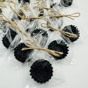 Può includere: Un gruppo di piccoli favori a forma di pneumatico nero avvolti in sacchetti di cellophane trasparenti con fiocchi di spago.