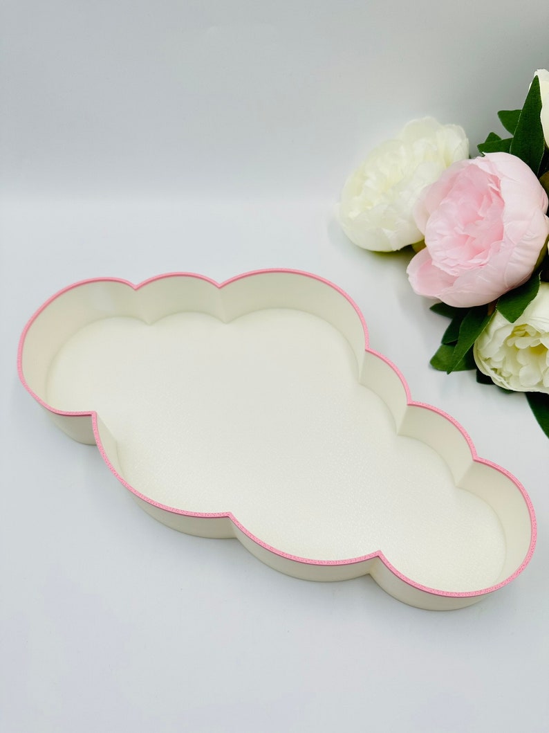 May include: A white cloud-shaped tray with a pink trim. The tray is made of a smooth, textured material.
