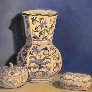 May include: A still life painting featuring a large, ornate vase and two smaller decorative containers. The objects are white with blue floral patterns, set against a blue backdrop. The vase has a unique shape, and the containers have lids.