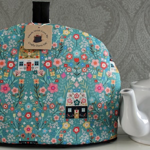 Könnte beinhalten: Türkise Teekanne mit einem Blumenmuster mit kleinen Häusern und dem Text "Made with Love by Crafty Doris UK".
