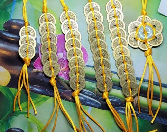 May include: Six strands of Chinese lucky coins strung together with yellow cords. Each strand has a different number of coins, ranging from 8 to 12. The coins are gold-colored and have Chinese characters on them.