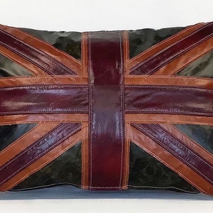 Puede incluir: Una almohada de cuero marrón, burdeos y verde con un diseño de Union Jack. La almohada está hecha de paneles de cuero cosidos.
