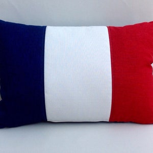May include: A decorative pillow with the colors of the French flag. The pillow is blue, white, and red.
