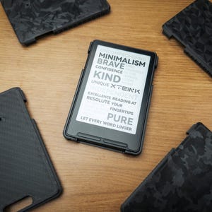 May include: A black e-reader device with a screen displaying text including "MINIMALISM," "BRAVE," "KIND," "XTEINK," and "PURE," surrounded by four distinct black protective cases featuring various textured patterns on a wooden surface.
