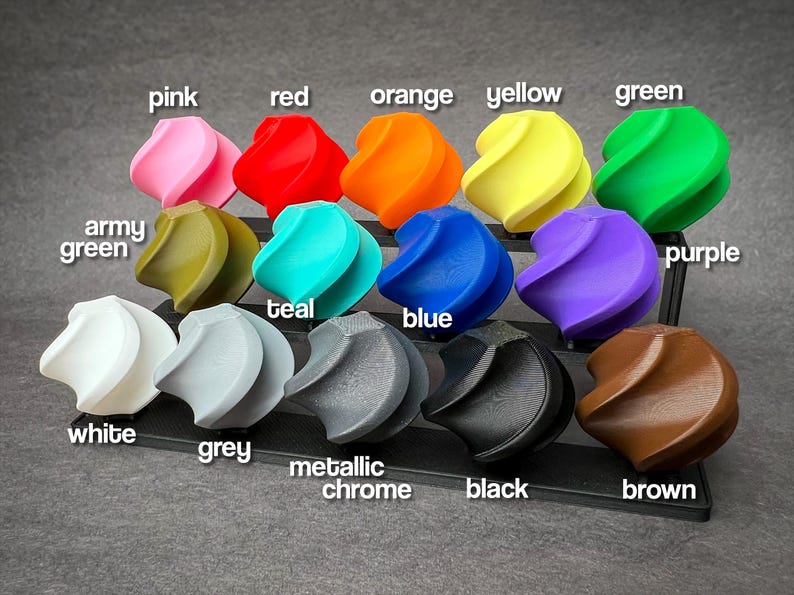 May include: A collection of twelve colorful, abstract, spiral-shaped objects. Colors include pink, red, orange, yellow, green, army green, teal, blue, purple, white, grey, metallic chrome, black, and brown. Each object is labeled with its respective color.