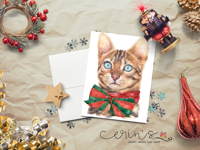 May include: A watercolor painting of a brown tabby cat wearing a red and green bow tie. The cat has blue eyes and is looking at the viewer. The background is white.