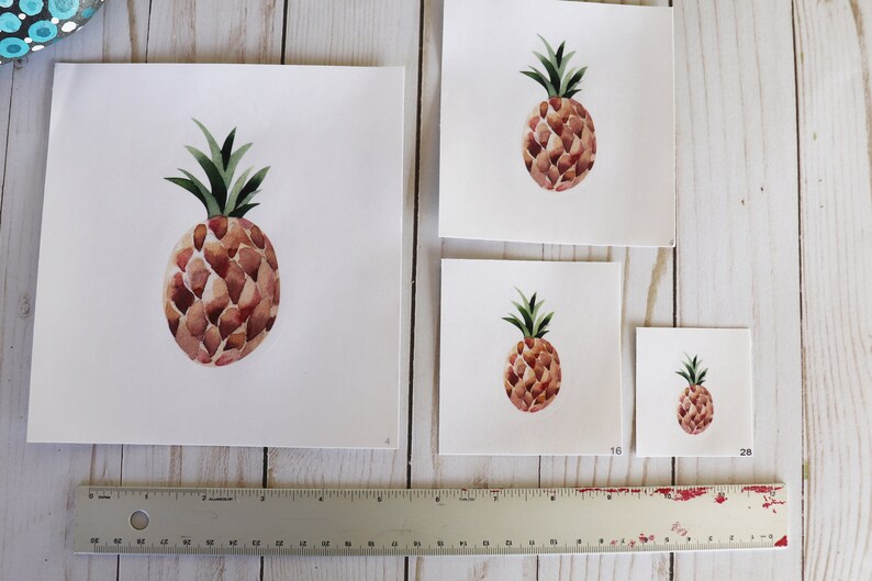 Pode incluir: Quatro impress&otilde;es de abacaxi de aquarela de tamanhos diferentes em papel branco. O abacaxi &eacute; marrom com o topo verde. As impress&otilde;es s&atilde;o etiquetadas com os tamanhos 16 e 28.
