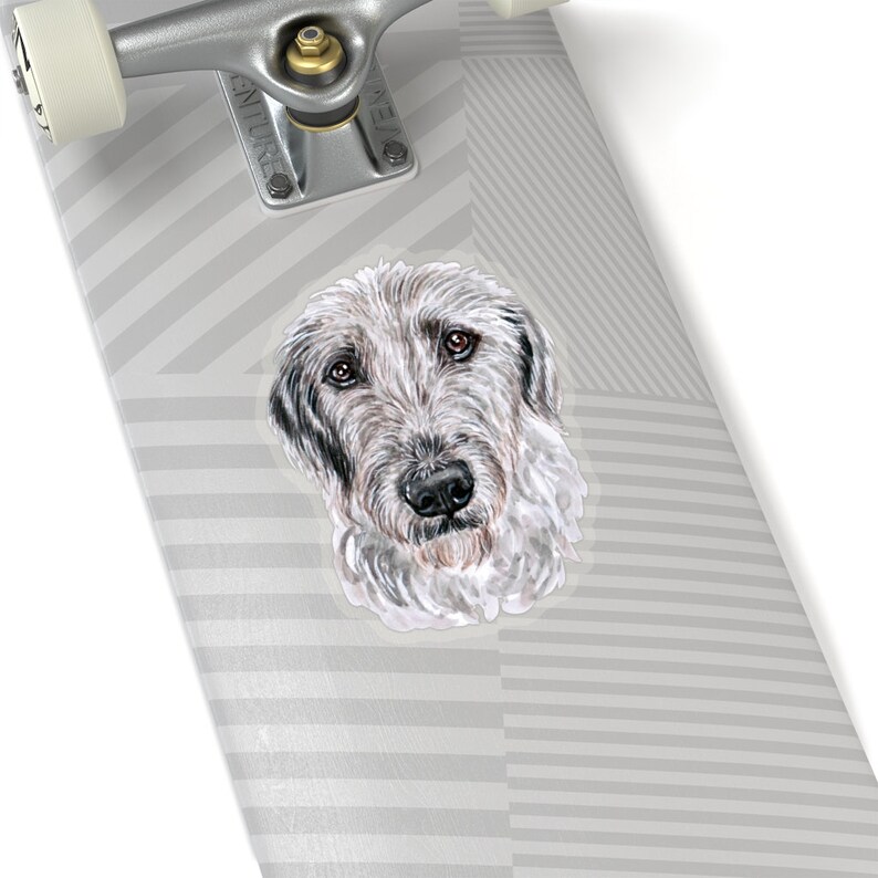 May include: A sticker featuring a watercolor illustration of an Irish Wolfhound dog's head. The dog has a white and gray coat, with black eyes and nose. The background is a gray and white striped pattern.