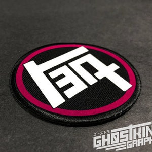 May include: A black and white embroidered patch with a red border. The patch features the Japanese characters for "Toyota" in a stylized font.