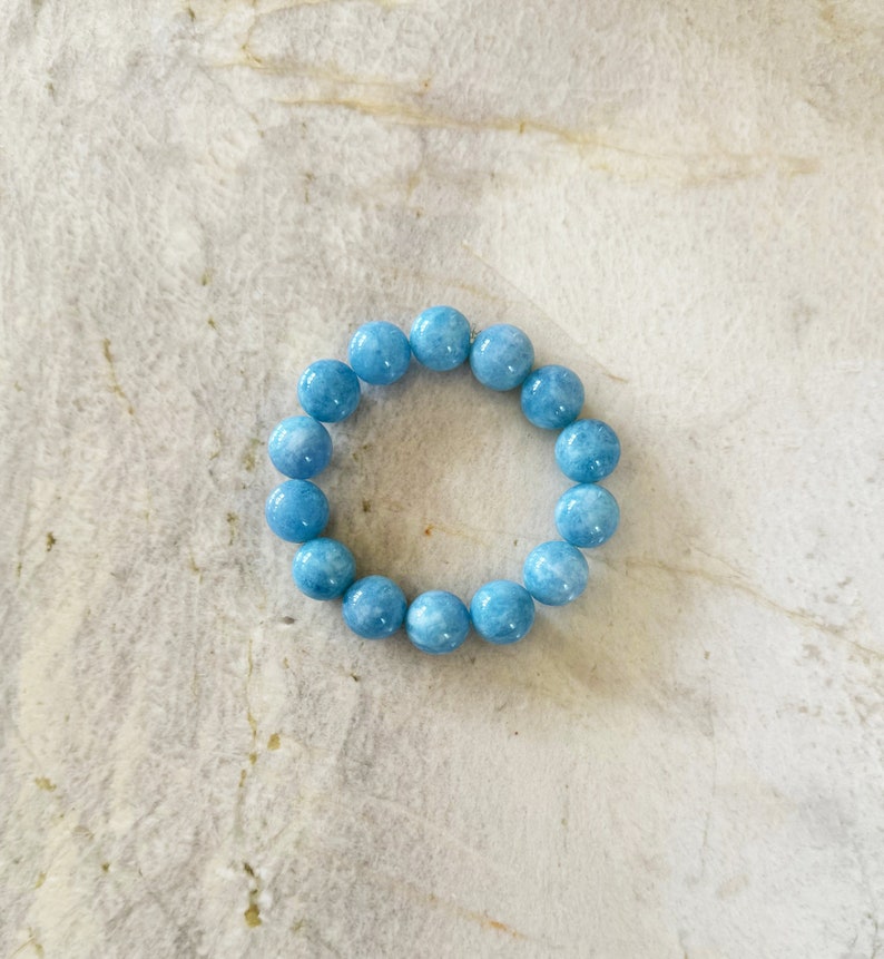 K&ouml;nnte beinhalten: Ein hellblaues Edelstein-Armband mit runden Perlen.