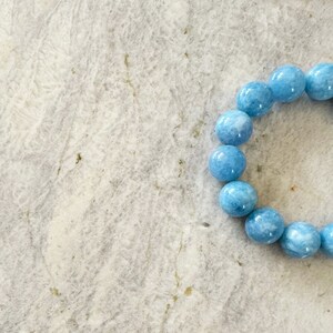 K&ouml;nnte beinhalten: Ein hellblaues Edelstein-Armband mit runden Perlen.