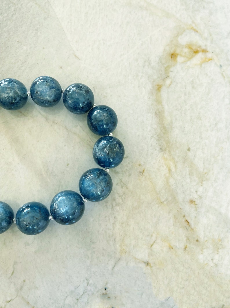K&ouml;nnte beinhalten: Ein blaues Edelstein-Armband mit runden Perlen. Das Armband besteht aus nat&uuml;rlichen Steinen und ist auf einem Silberdraht aufgef&auml;delt.