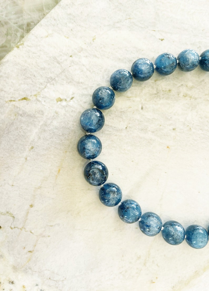 K&ouml;nnte beinhalten: Ein blaues Edelstein-Armband mit runden Perlen. Die Perlen sind hellblau mit einem leicht dunkleren Blauton.