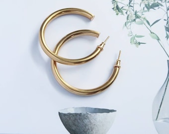 May include: A pair of large, gold hoop earrings. The earrings are thick and have a smooth, polished finish.