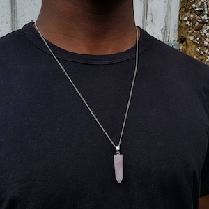 Può includere: Una collana con catena d'argento con un ciondolo di cristallo rosa a forma di punta.