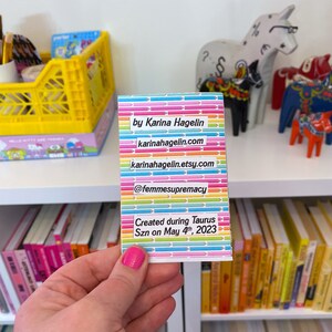 May include: A rainbow-colored card with the text "by Karina Hagelin", "karinahagelin.com", "karinahagelin.etsy.com", "@femmesupremacy", "Created during Taurus Szn on May 4th, 2023".