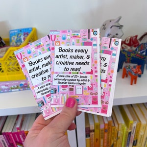 May include: Three pink mini-zines with a colorful pattern of illustrations. The text on the front reads "Books every artist, maker, & creative needs to read. A mini-zine of 25+ books personally curated by artist & librarian Karina Hagelin."