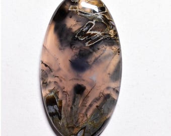May include: A pink, gray, and black agate cabochon with a unique dendritic pattern. The cabochon is oval shaped and has a smooth, polished surface.