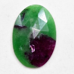 May include: An oval-shaped gemstone with a faceted cut. The gemstone is green with a purple section.