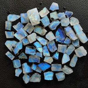 May include: A collection of iridescent blue and white moonstone chips. The chips are various sizes and shapes, with a natural, rough texture.