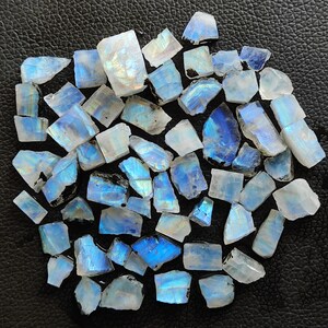 May include: A collection of iridescent blue and white moonstone chips. The chips are various sizes and shapes, with a natural, rough texture.