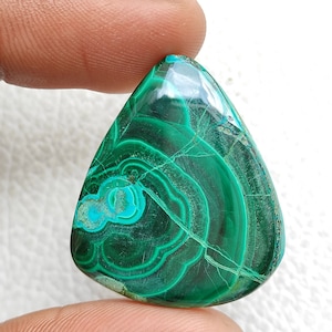 May include: A green malachite cabochon gemstone with a teardrop shape and intricate swirling patterns. The stone has a polished finish and is suitable for jewelry making.