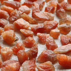 May include: A collection of sunstone rough, a variety of feldspar, with a reddish-orange color and a shimmery, iridescent sheen.
