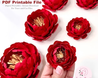 May include: Five red paper peonies with gold centers. The peonies are arranged on a white surface. The text "PDF Printable File" is at the top of the image. The text "Digital Printables - Instant Download" is below the first line of text. The text "For Trace and Cut Files" is below the second line of text. The text "Crafty Sagittarius" is at the bottom of the image. The text "PREMIUM PAPER FLOWER TEMPLATES" is below the first line of text.
