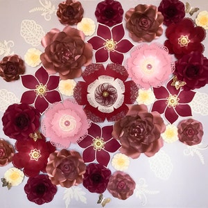 K&ouml;nnte beinhalten: Eine Sammlung von Papierblumen in den Farben Rosa, Rot und Wei&szlig;. Die Blumen sind in einem Kreis auf einem hellgrauen Hintergrund angeordnet.
