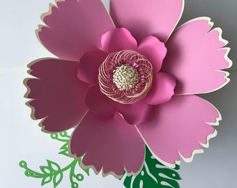 May include: A large pink paper flower with a white center and green leaves. The flower is layered and has a 3D effect.