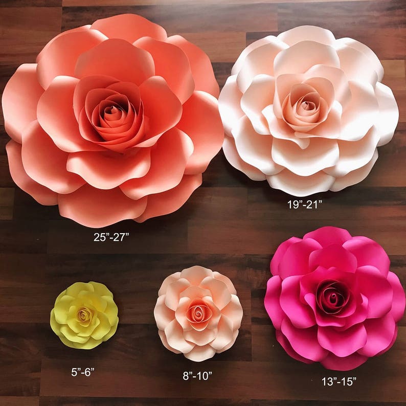 May include: Five paper flowers of varying sizes and colors. The largest flower is peach, 25-27 inches in diameter. The next largest is cream, 19-21 inches in diameter. The next is pink, 13-15 inches in diameter. The next is peach, 8-10 inches in diameter. The smallest is yellow, 5-6 inches in diameter.