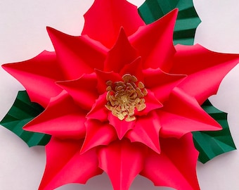 May include: A large, red paper poinsettia flower with a gold glitter center. The flower is surrounded by green paper leaves.