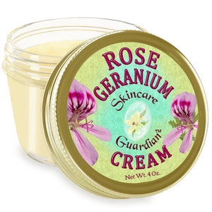 May include: A glass jar with a gold lid containing a white cream. The lid has a label with a floral design and the text "Rose Geranium Skincare Guardian Cream Net Wt. 4 Oz."