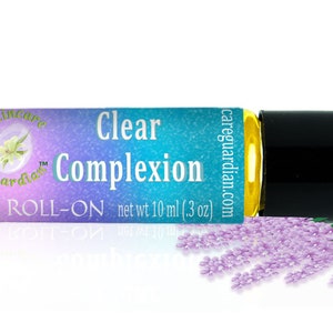 Könnte beinhalten: Eine transparente Roll-on-Flasche aus Glas mit schwarzem Verschluss. Das Etikett ist blau und lila mit dem Text "Skincare Guardian" und "Clear Complexion Roll-On net wt 10 ml (0.3 oz)". Die Flasche ist von lila Blüten umgeben.