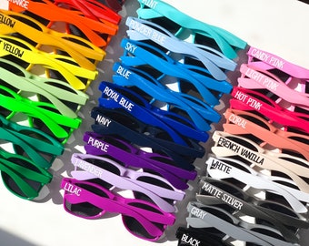 May include: A collection of colorful sunglasses with various color names printed on the frames, including yellow, light yellow, powder blue, sky blue, royal blue, navy, purple, lavender, lilac, candy pink, light pink, hot pink, coral, French vanilla, white, matte silver, gray, and black.