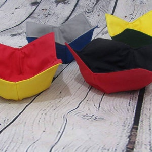 May include: Four fabric bowls in different colors. The bowls are folded into a bowl shape and are made of a soft, flexible fabric. The bowls are red, yellow, blue, and green.
