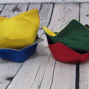 May include: Three fabric bowl cozies in different colors. The top cozie is yellow, the middle cozie is green, and the bottom cozie is red.