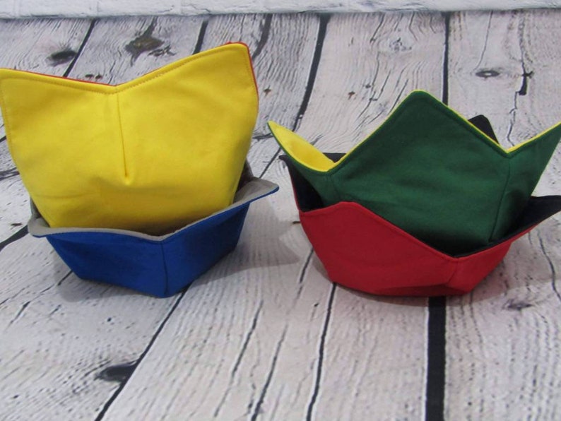 May include: Three fabric bowl cozies in different colors. The top cozie is yellow, the middle cozie is green, and the bottom cozie is red.