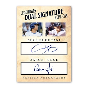 May include: A baseball card featuring Shohei Ohtani and Aaron Judge. The card has the text "LEGENDARY DUAL SIGNATURE REPLICAS" at the top. Below the text are images of the players, and their replica signatures are displayed below their names. The bottom of the card reads "REPLICA AUTOGRAPHS."