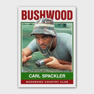 May include: A poster featuring a man in a camouflage bucket hat and a green shirt, holding a brown object. The poster has the word "BUSHWOOD" in red at the top and "CARL SPACKLER" and "BUSHWOOD COUNTRY CLUB" at the bottom.