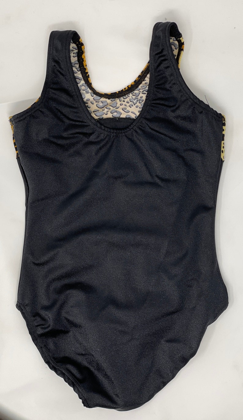 Pu&ograve; includere: Costume da bagno intero nero con scollo tondo e schiena bassa. La fodera interna presenta un motivo leopardato nei toni del beige, marrone e nero. Le spalline e i bordi sono rifiniti con lo stesso motivo leopardato.
