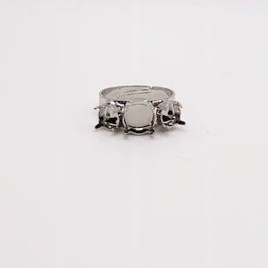 May include: Silver ring with three empty square settings for gemstones.