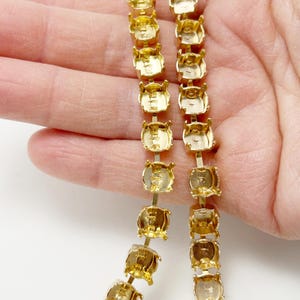 May include: A white ceramic mug with a black handle and the text "But First, Coffee" in a black, handwritten-style font. The mug is on a white surface.