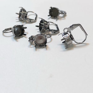 May include: Six silver earring settings with a round bezel for adding a stone or cabochon. The settings have a lever back closure.