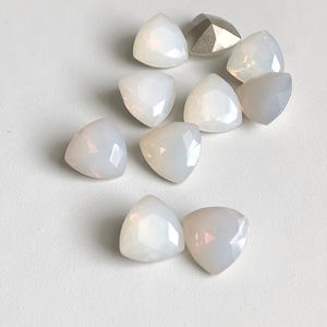 May include: A group of ten white opal gemstone cabochons in a triangular shape. The stones are arranged in a circle with one stone in the center.