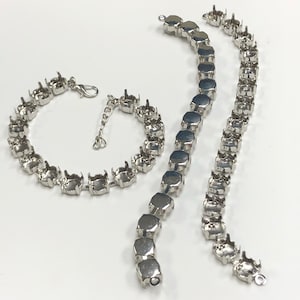 May include: Three silver metal chains with prongs for attaching rhinestones. The chains are different lengths and are arranged in a curved shape.