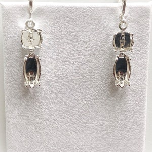 May include: A pair of silver dangle earrings with two oval-shaped settings. The earrings have a lever back closure.
